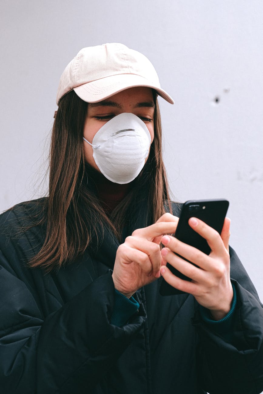 woman in face mask using smartphone