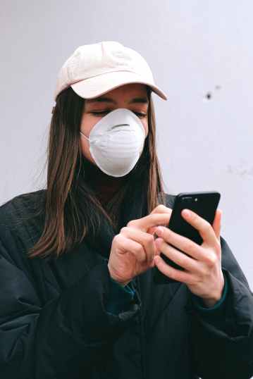 woman in face mask using smartphone