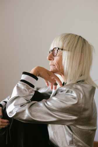 pensive elderly woman in eyeglasses and trendy bomber